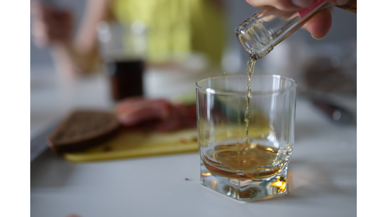 Female hand pours liquor drink into glass