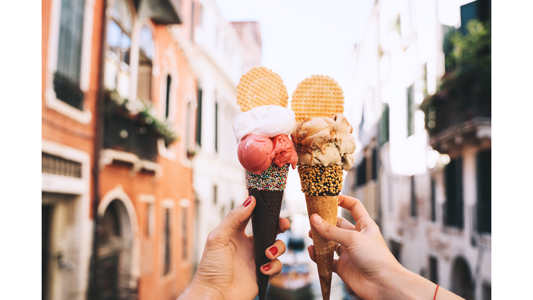Beautiful and delicious italian gelato in waffle cone in front of streets and bridges of Venice.