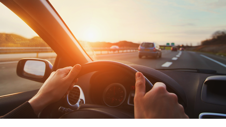 hands of car driver on steering wheel, road trip