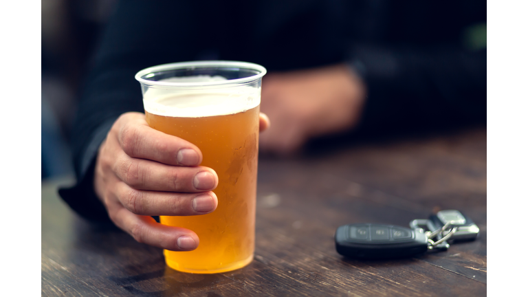 Man drinks beer and car keys are on the table. Concept of driving a car after alcohol consumption.