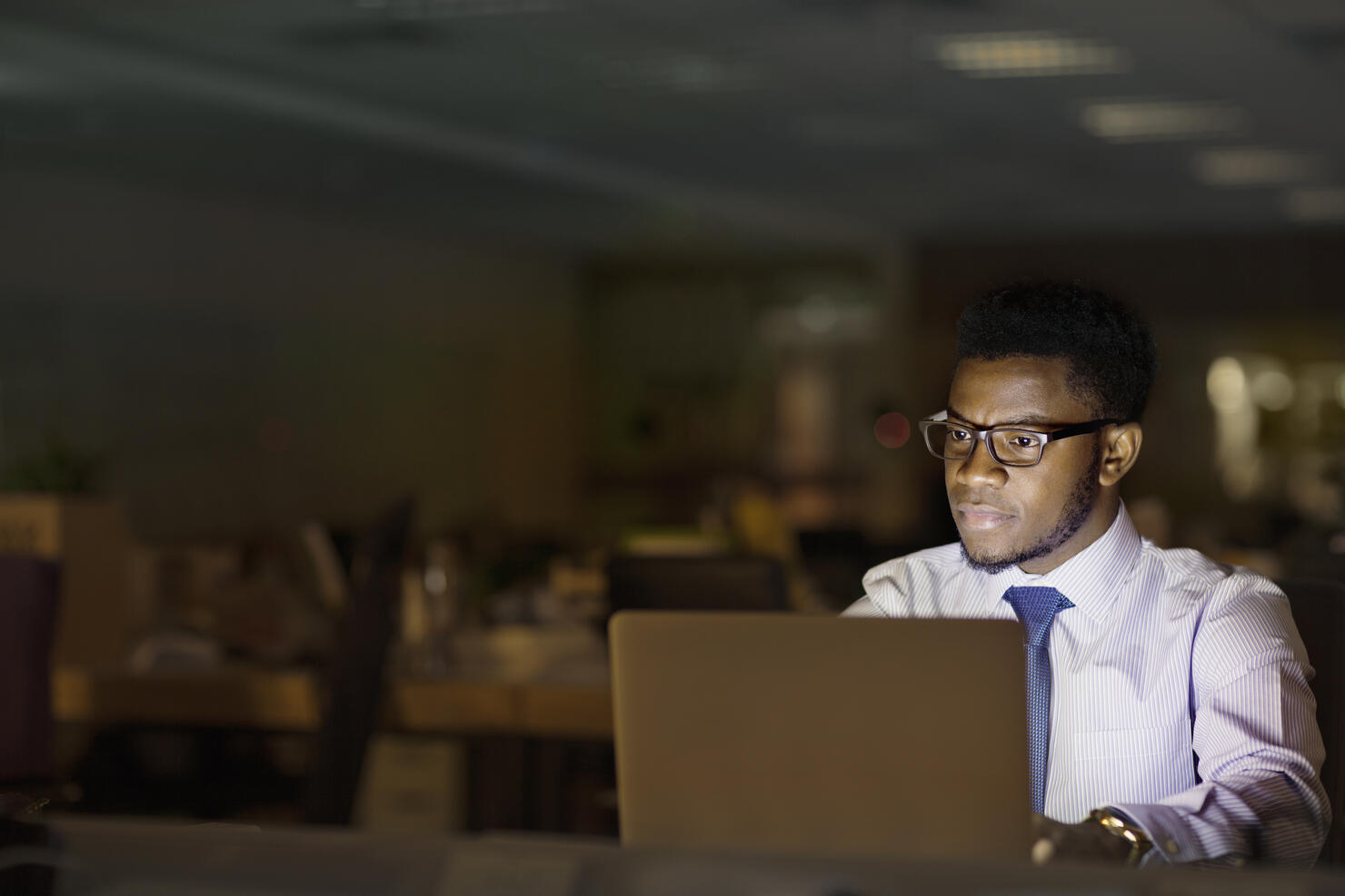 Man looking at laptop computer in office at night