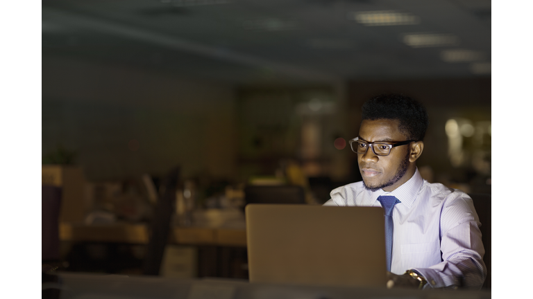 Man looking at laptop computer in office at night