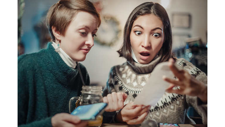 Asian woman stares at the check for dinner at the restaurant, her eyes bulging. The concept of inflation and devaluation of money and reduction of purchasing power of the population.
