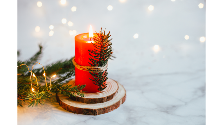 Christmas festive winter greeting card. White candle, wooden natural tray and pine fir tree branches. Home interior decoration.