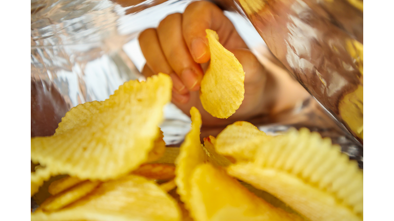 Hand hold potato chips inside snack foil bag