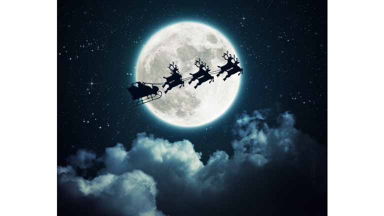 Santa Claus in a sleigh flying over the moon in the night