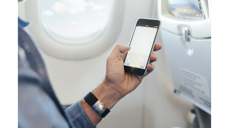 Man sitting on an airplane holding smartphone