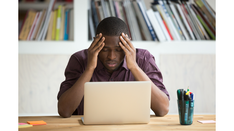 Frustrated black man feeling depressed after fail sitting with laptop