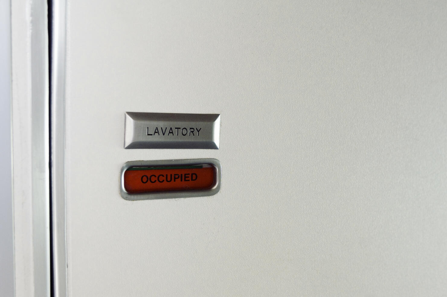 Close-up of airline lavatory door with sign reading 'occupied'