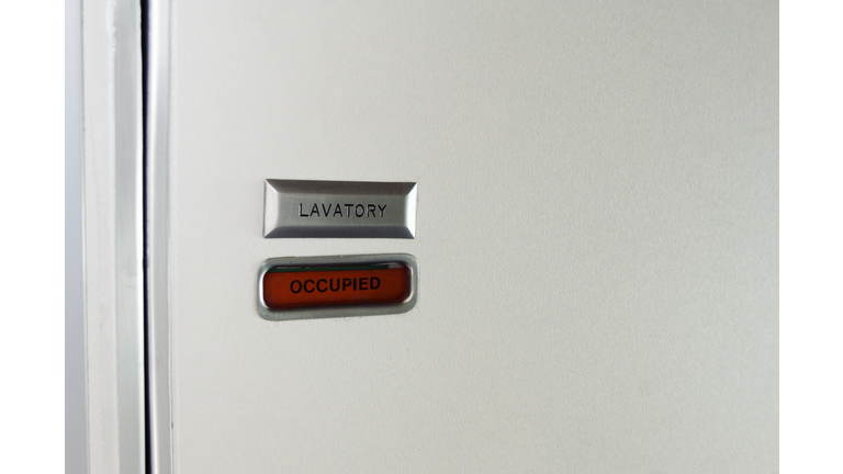 Close-up of airline lavatory door with sign reading 'occupied'