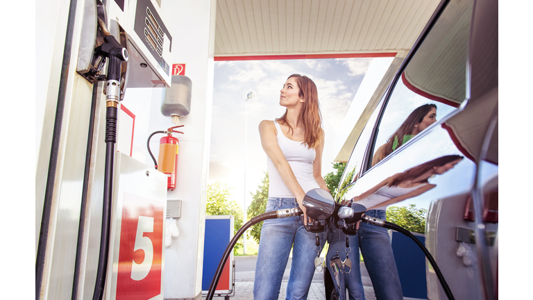 Pretty young woman refuel the car