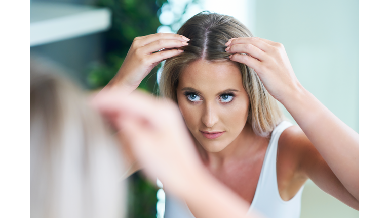 Happy woman brushing hair in bathroom having problem with hair loss