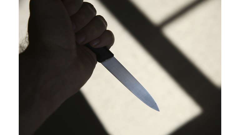 A hand holding a knife in shadow. This image can be used to represent stabbing or murder.