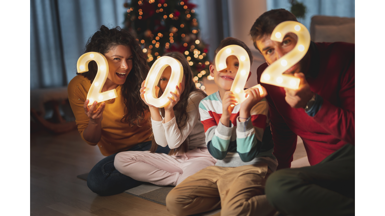 Family celebrating New Year holding illuminative numbers 2022