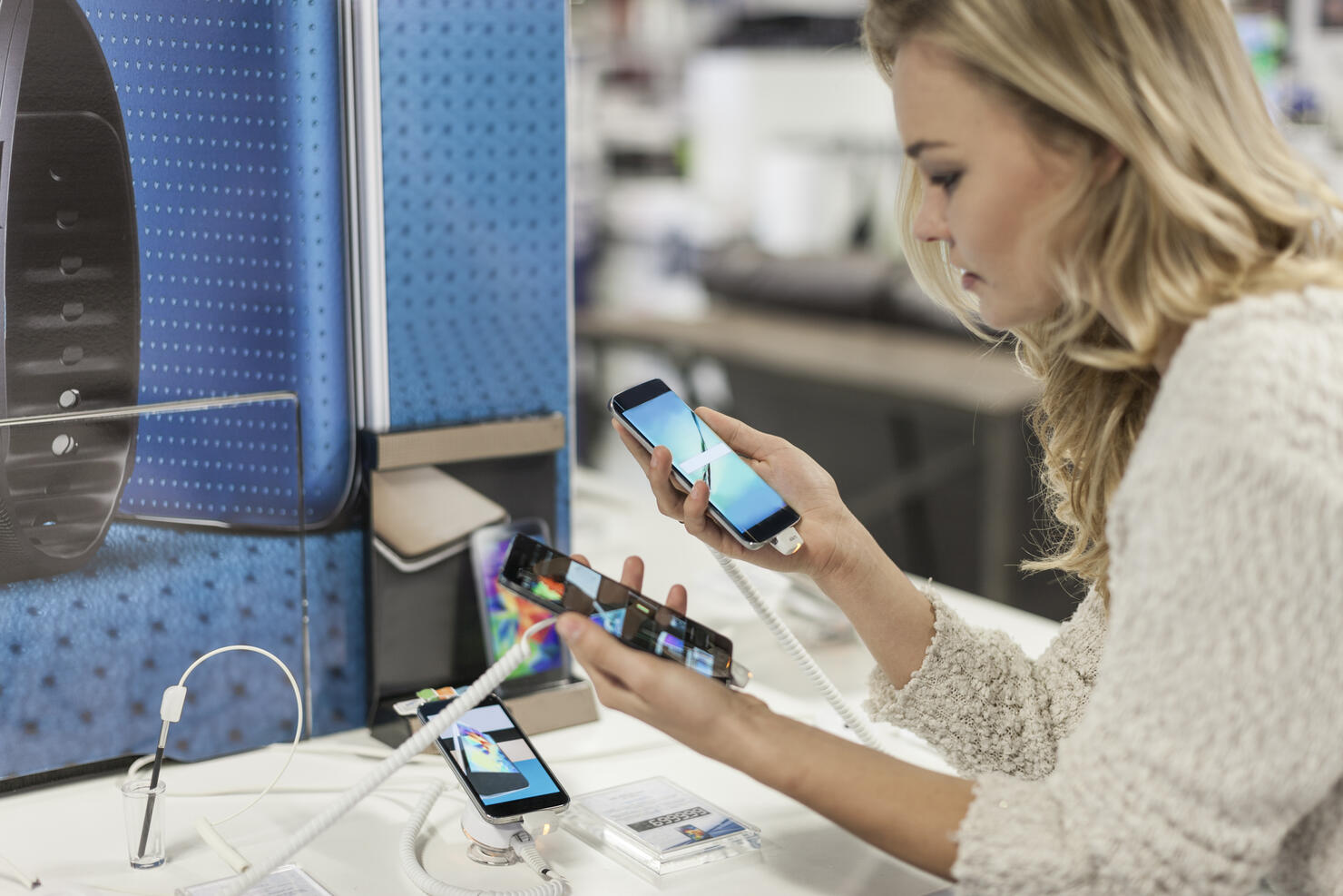 Young woman comparing two smartphones in a shop