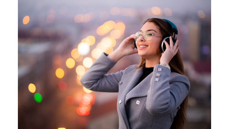 Beautiful young women listening to music on the rooftop