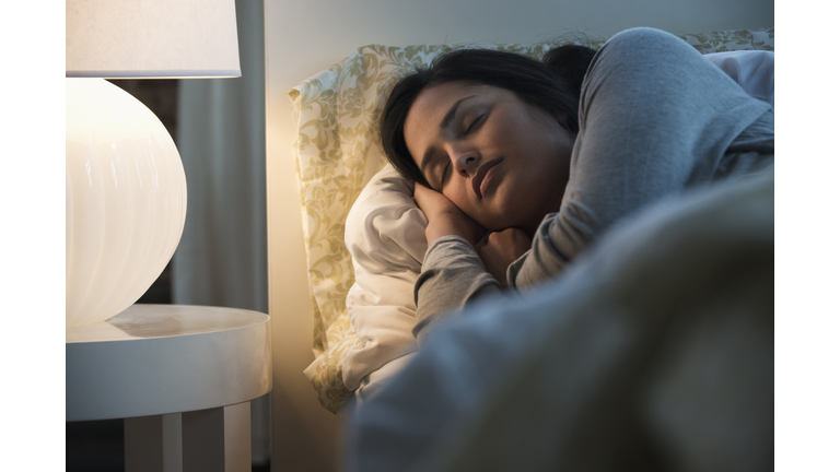 Lamp illuminating sleeping Hispanic woman