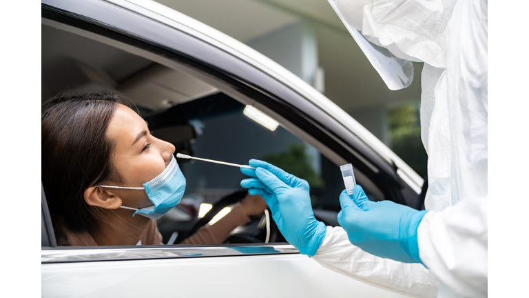 Asian woman Drive Thru COVID-19 testing with PPE medical staff