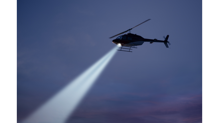 Police helicopter shining a light beam in the dark sky