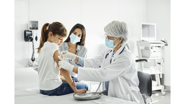 Girl receiving COVID-19 shot and looking at her arm.