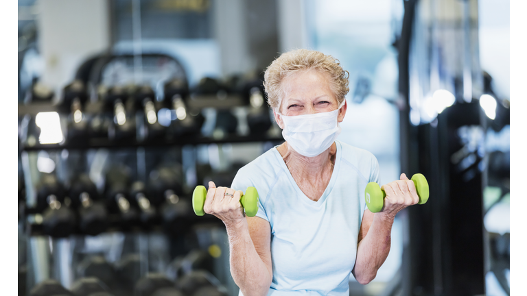 Senior woman working out at the gym, wearing face mask