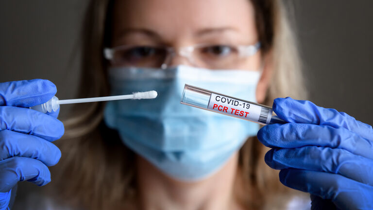 Coronavirus swab collection kit in doctor hands, woman in medical mask holds tube of COVID-19 PCR test