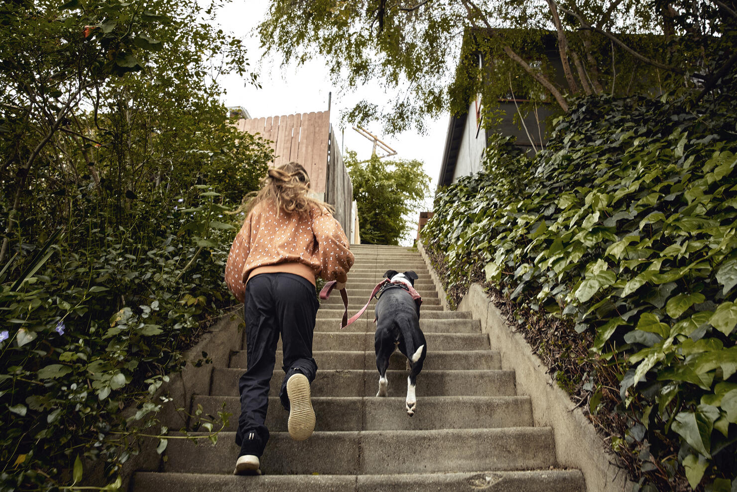 Young girl running up steps while walking dog