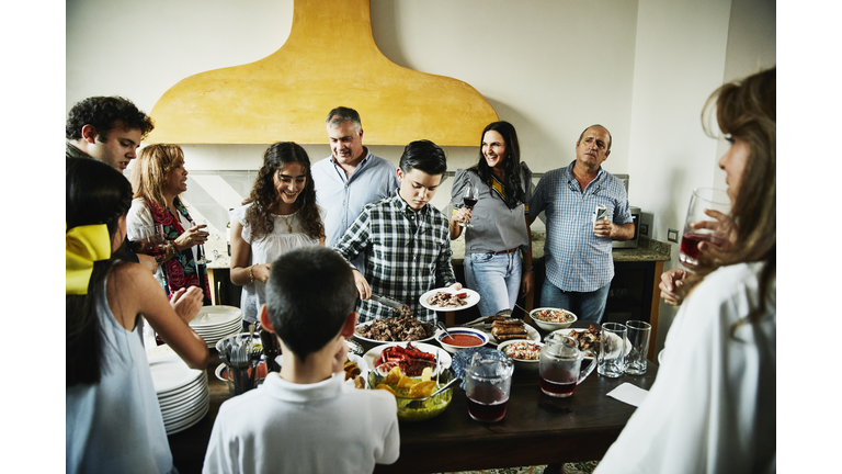 Boy serving himself food in kitchen during multigenerational family party