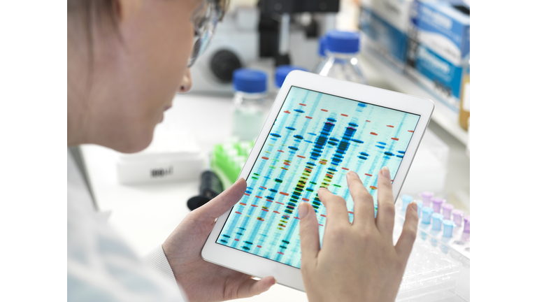 Female scientist examining DNA sequence results on digital tablet in laboratory