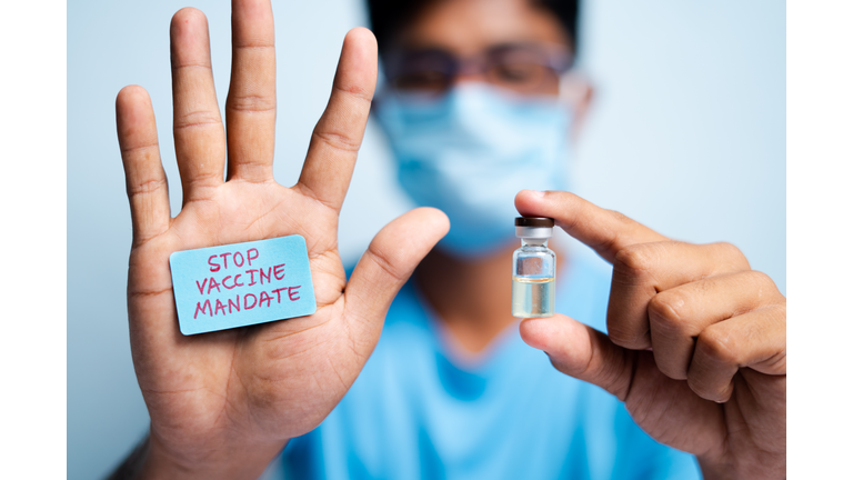 Focus on hands, Young man with medical face mask showing stop vaccine mandate - concept vaccine hesitancy.