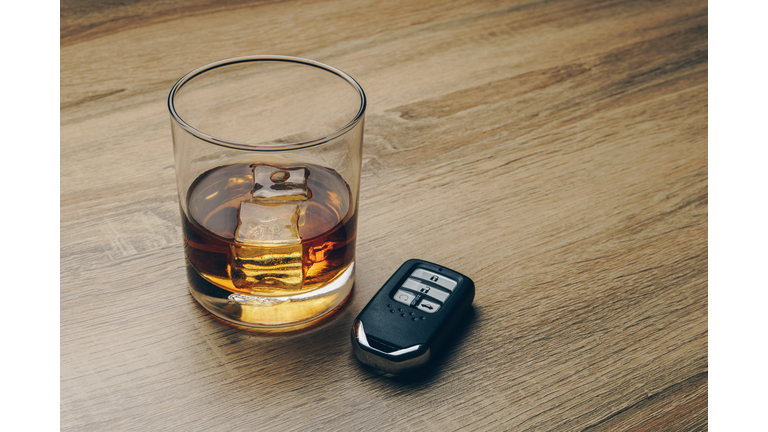 close up of a glass of bourbon whiskey and a remote car key