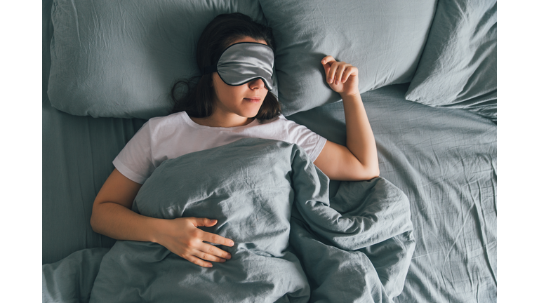 woman sleep in eye patch in grey bed. copy space