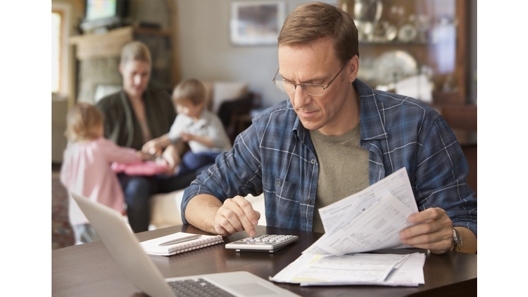Father paying bills with family behind him