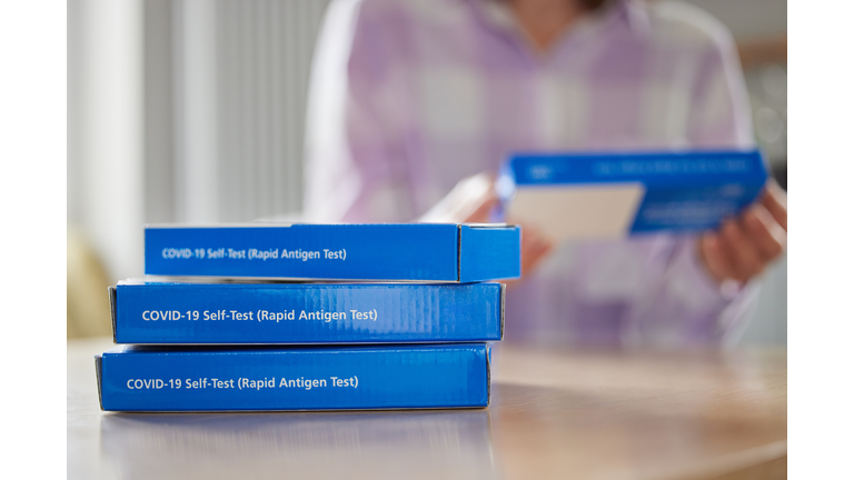 Close Up Of Woman At Home Reading Instructions On Supply Of Covid-19 Rapid Antigen Self-Testing Kits