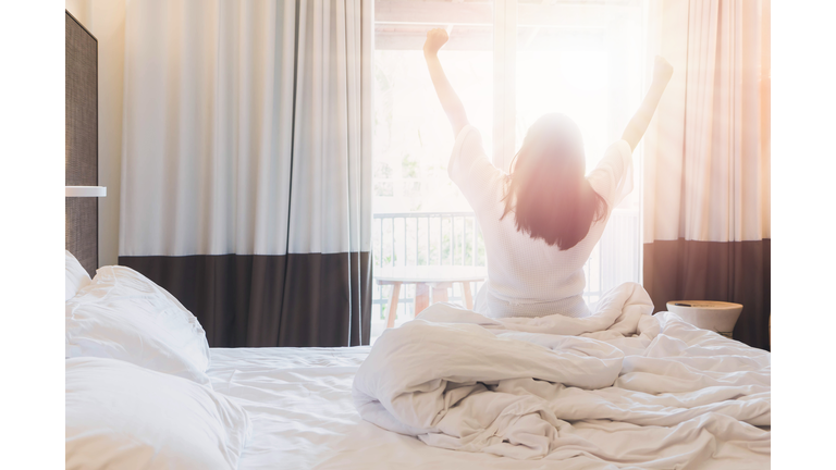 Asian women are staying in a hotel room after wake up on morning. Open the curtain in the room looking to outside view.Vintage tone.