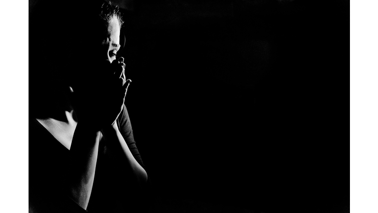 Woman in shadows crying on black