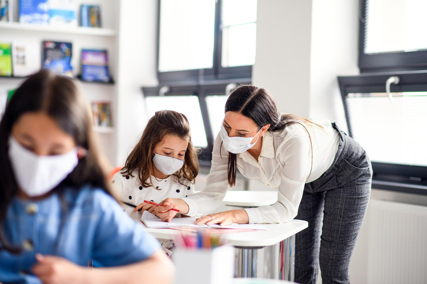 Teacher and children with face mask back at school after covid-19 quarantine and lockdown.