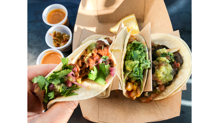 POV of Hand Holding Vegan Taco over Sauces and Pickles