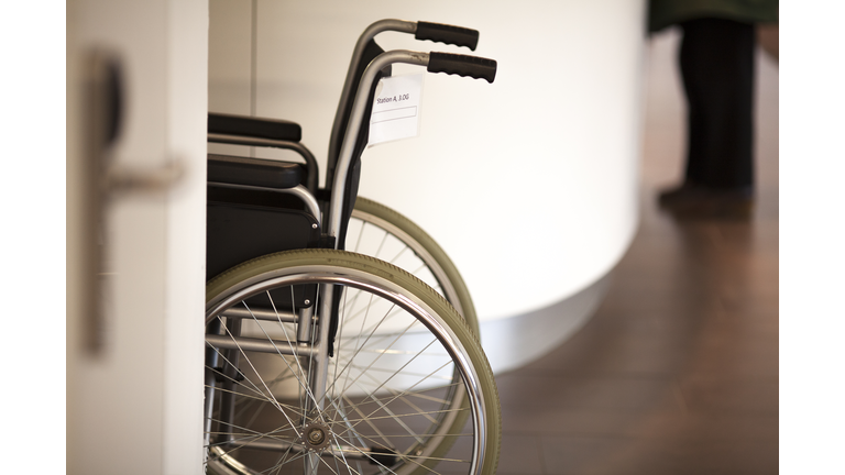 Wheel chair in the hospital corridor man standing in background