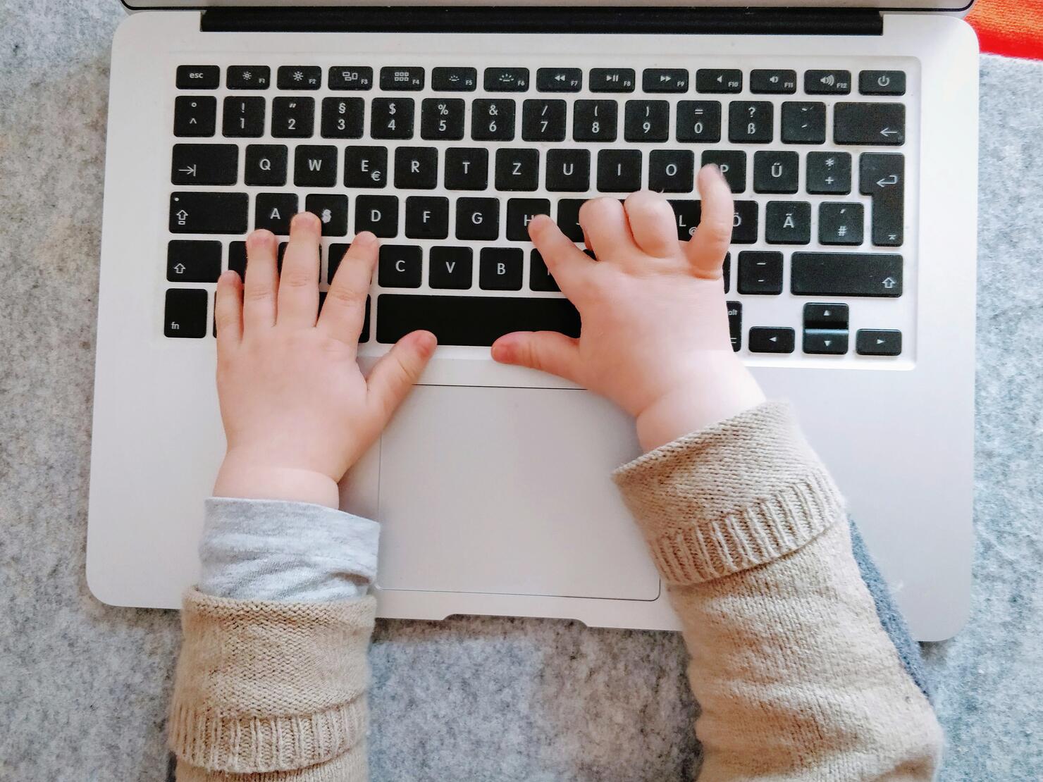 Close-Up Of Child Hands Using Laptop