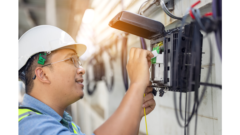 An internet technician is repairing or maintaining a fiber optic connection by opening a fiber optic connector.