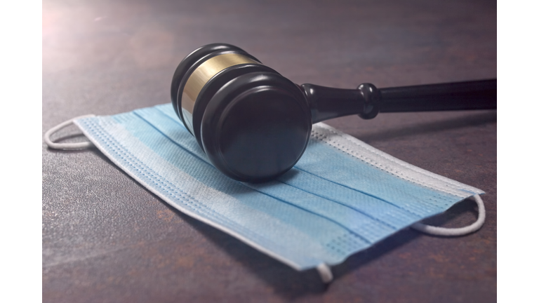 Close-up of a Judge Gavel Resting On A Protective Mask.