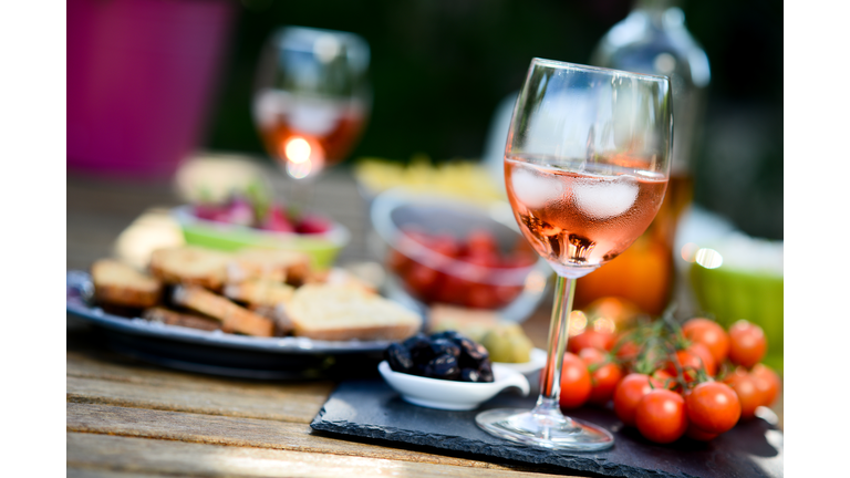 holiday summer brunch party table outdoor in a house backyard with appetizer, glass of rosÃ© wine, fresh drink and organic vegetables