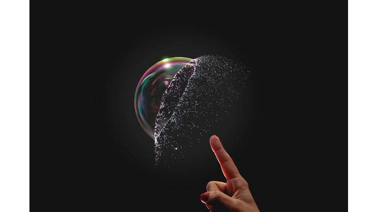 Cropped Image Of Hand Bursting A Bubble Against Black Backbround