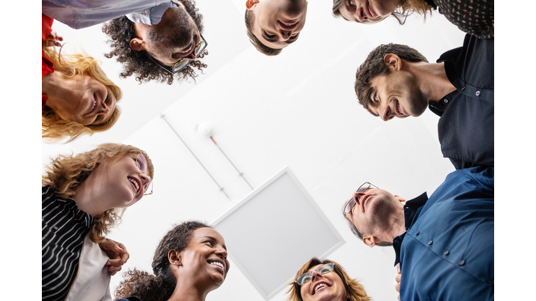 Smiling entrepreneurs huddling together in creative office
