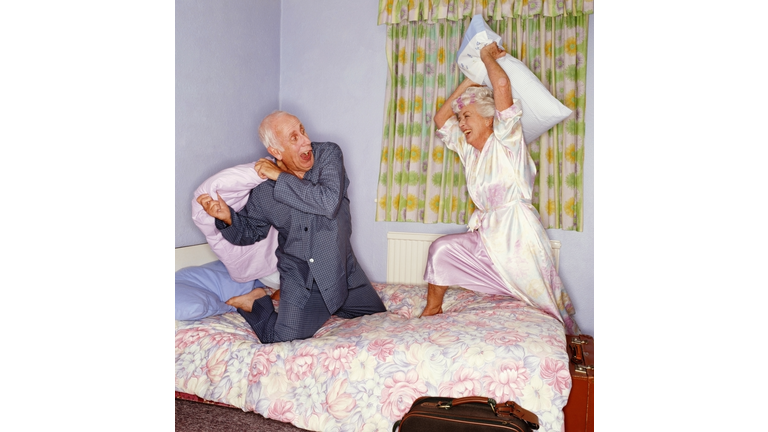 Senior couple having pillow fight on bed