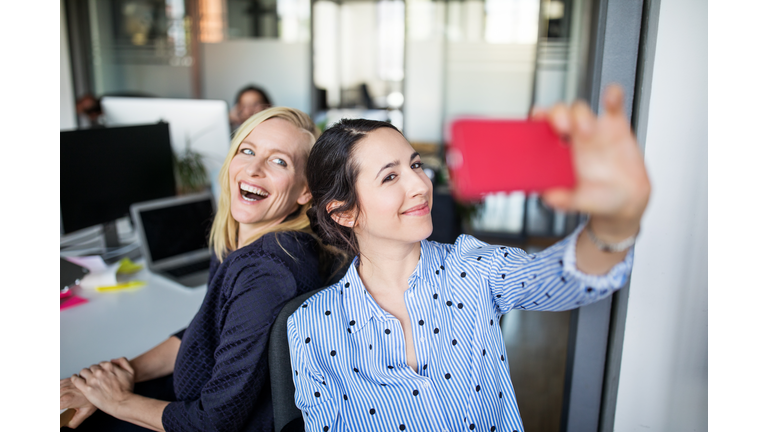 Businesswoman taking selfie with female colleague
