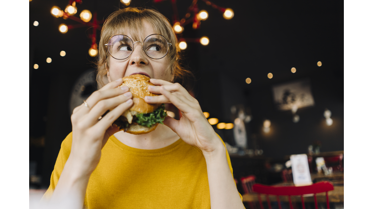 Young woman eating burger in a restaurant