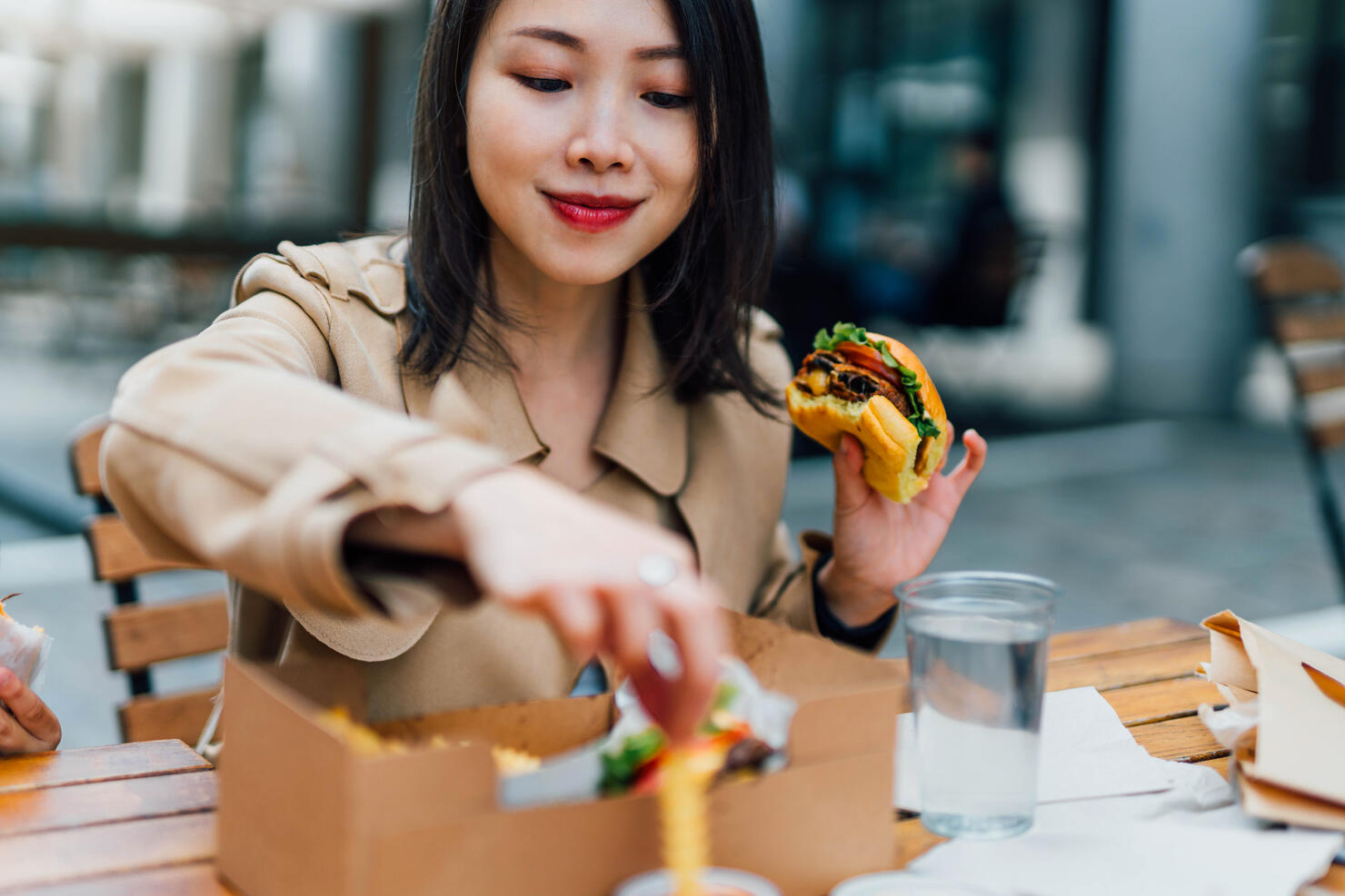 Young Woman Eating Burger And Chips Outdoors