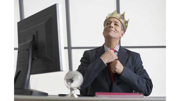 Businessman with crown sitting at desk